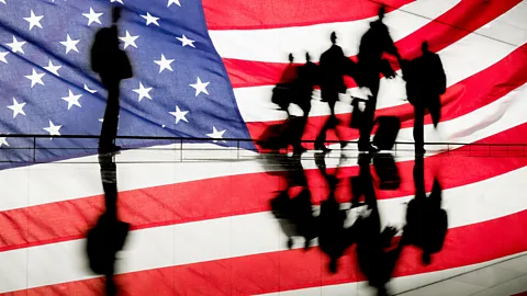 An American flag background, with a silhouette of people moving away from one person (Credit: Alamy)