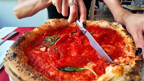 Person cutting an authentic neapolitan pizza marinara (Credit: Getty Images)