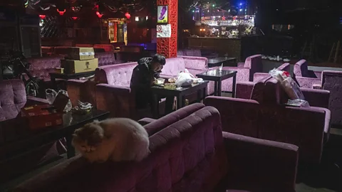 man sitting reading phone in empty bar (Credit: Gilles Sabrié/ New York Times/ Redux/ eyevine)