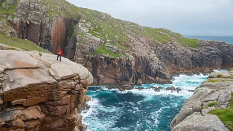 Hiker admiring the rocky coastline of Owey Island (Credit: Alamy)