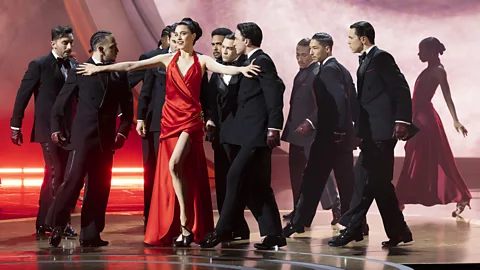 Margaret Qualley in a red dress on stage with dancers at the 2025 Academy Awards (Credit: Getty Images)