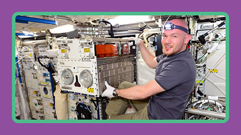 Astronaut Alexander Gerst moves laboratory equipment within the ISS.