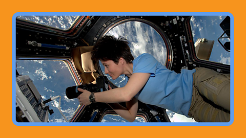 An astronaut looks through the windows of the ISS onto Earth below.