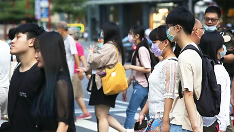 Pedestrians u2013 some wearing face masks and others without u2013 cross a road in Taiwan (Credit: Alamy)