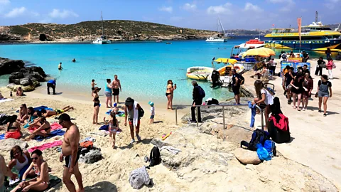 Crowds of people at the Blue Lagoon, Malta with boats to the right (Credit: Alamy)