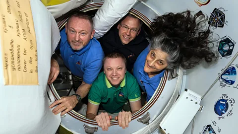 NASA astronauts Butch Wimore, Nick Hague, and Suni Williams, and Roscosmos cosmonaut Aleksandr Gorbunov peek out of a hatch on the ISS (Credit: Alamy)