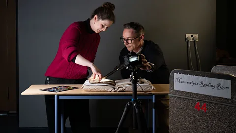 Sally Kilby and Błażej Mikuła photograph inside the folds of a Medieval manuscript (Credit: Cambridge University Library)