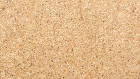 The texture of chipboard - wood chips of varying shades are glued together.