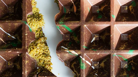Close up of broken bar of Dubai chocolate, showing the green pistachio and knafeh inside (Credit: Getty Images)