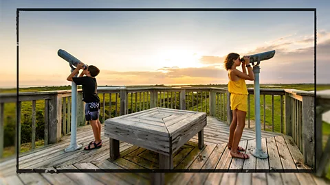 Two children look through sightseeing telescopes at the Outer Banks in North Carolina, United States (Credit: Getty Images)