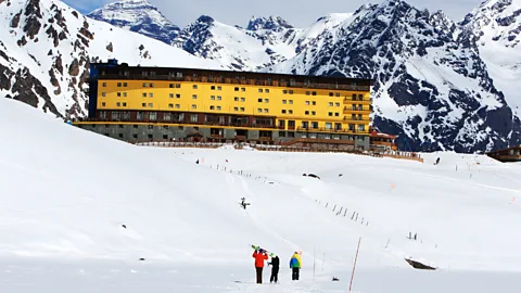 View of the Portillo Ski Resort Hotel Lodge with snowboarders in the foreground (Credit: Getty Images)