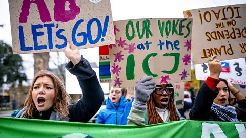 Climate protestors hold placards outside the ICJ in the Netherlands in 2024 (Credit: Getty Images)