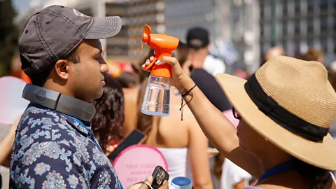 A tourist sprays her companion with a water mister (Credit: Alamy)