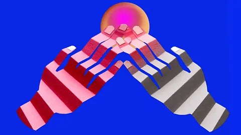 Two hands cut out of paper - one red, the other gray – touch a multicoloured ball. The background is bright blue (Credit: Serenity Strull/ BBC)