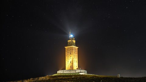 The Tower of Hercules shines bright against the night sky, the tower is lit and the lighthouse beacon illuminates the sky