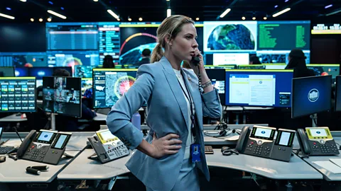Rebecca Ferguson at a desk surrounded by screens, listening on the phone, in A House of Dynamite (Credit: Eros Hoagland/ Netflix)