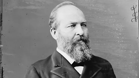 Black-and-white portrait of President James Garfield. He is a bearded man with his hair brushed away from his face, wearing a white shirt and black jacket, looking to the right of the frame (Credit: Getty Images)