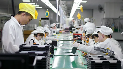 People wearing white caps and gowns manufacture lithium batteries at a workshop in China (Credit: Alamy)