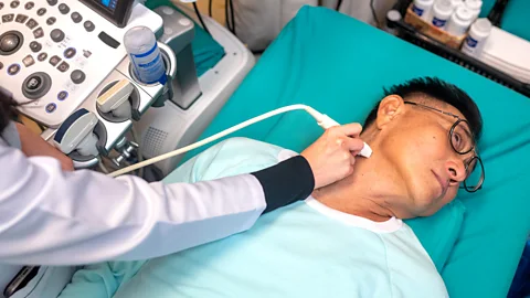 Man lying on a hospital bed getting a test on his thyroid (Credit: Getty Images)
