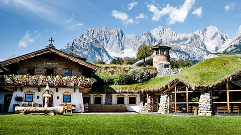 Exterior of Stanglwirt hotel decorated with flower boxes under snow dusted peaks of the Wilder Kaiser mountains (Credit: Stanglwirt)