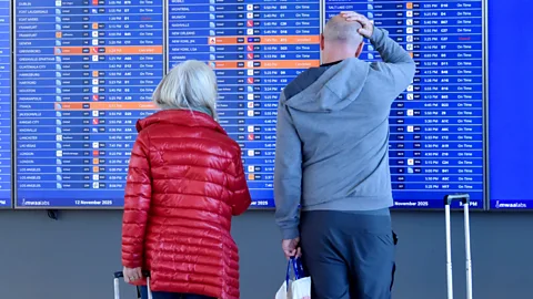 A couple look at a departure board in an airport (Credit: Getty Images)