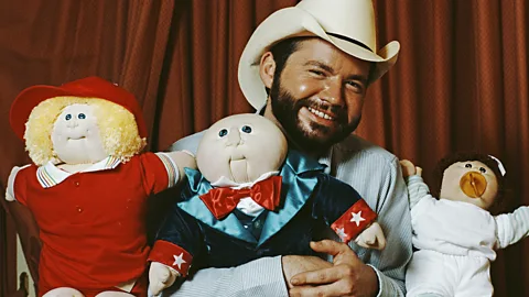Four women smiling at a Cabbage Patch Kid doll (Credit: Getty Images)