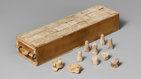 A photo of an ancient Egyptian game box with playing pieces and knuckle bones for dice