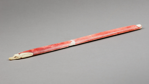 A photo of an ivory throwing stick with jackal head.