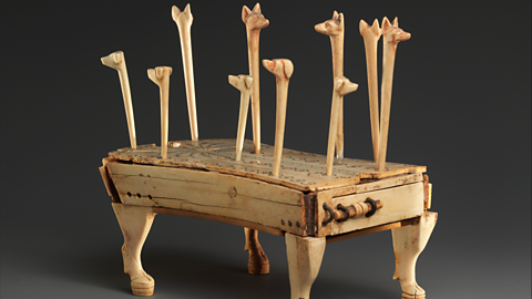 A photo of a Hounds and Jackals game board with playing pieces with the heads of dogs and jackals on them