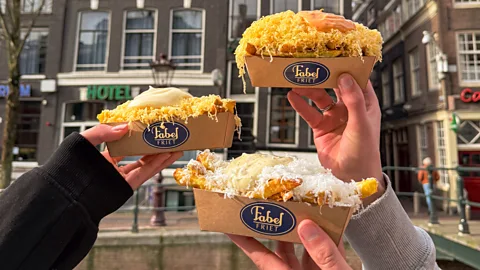 Close up of three hands holding cartons of fries with Fabelfriet label on them (Credit: FabelFriet)
