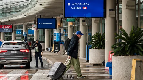A man carries bags at the entrance to an Air Canada Airport terminal (Credit: Getty Images)