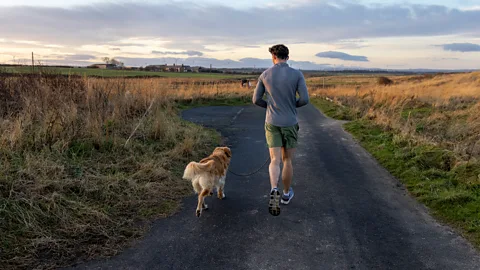A man running on a countryside with his dog (Credit: Getty Images)