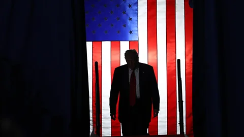 A silhouette of President Donald Trump with an American flag hanging behind him (Credit: Getty Images)