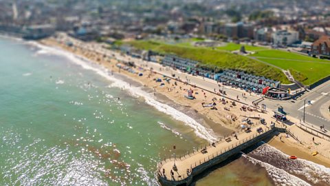A busy beach in summer time with the town visible behind 