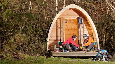 Couple preparing for a hike in front of camping pod 