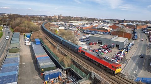 Arial view of Freight Container Train passing through a town
