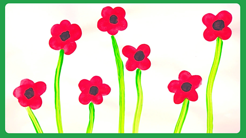 A white piece of paper with red painted petals on and black dots in the middle, with green stalks