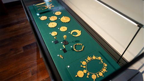 A collection of Asante gold in a museum. There are necklaces, bracelets and brooches.