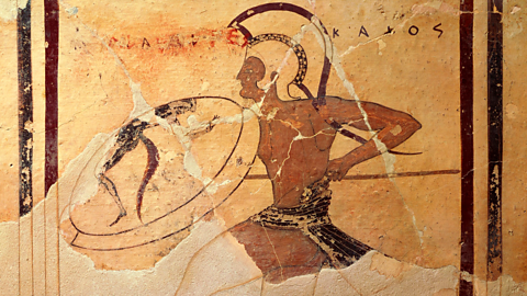 A terracotta fresco, painting of a Greek hoplite. They carry a spear and shield, and wear a helmet.
