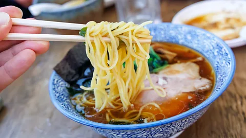 A diner picks up ramen on their chopsticks (Credit: Getty Images)