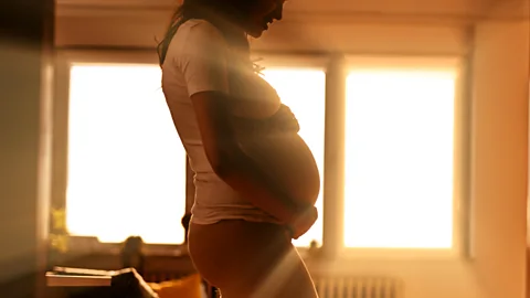 Pregnant woman standing in front of brightly backlit window (Credit: Getty Images)