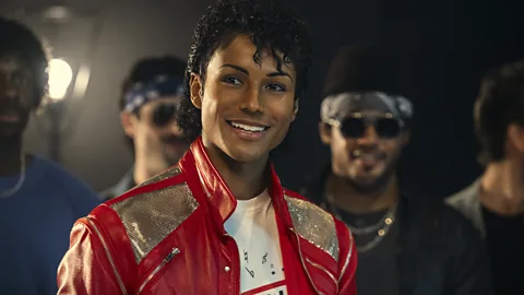 A still of Jaafar Jackson wearing a red leather jacket and smiling at the camera in Michael biopic (Credit: Universal)