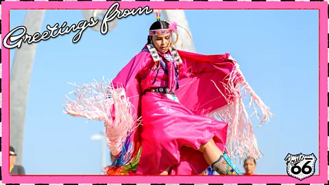 A postcard-style image of a Native American dancer in bright pink regalia with the words "Greetings from" and a Route 66 shield in the corner (Credit: First Americans Museum/ Serenity Strull/ BBC)