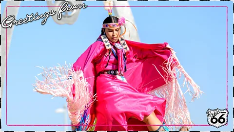 A postcard-style image of a Native American dancer in bright pink regalia with the words "Greetings from" and a Route 66 shield in the corner (Credit: First Americans Museum/ Serenity Strull/ BBC)