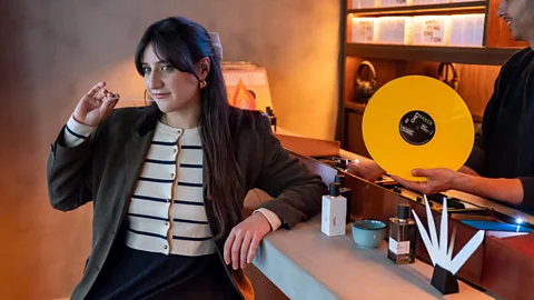 A young woman stands next to countertop with selection of perfumes at a vintage perfume shop (Credit: Hervé Lassïnce)