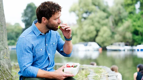 A man eating fruit next to a river (Credit: Getty Images)