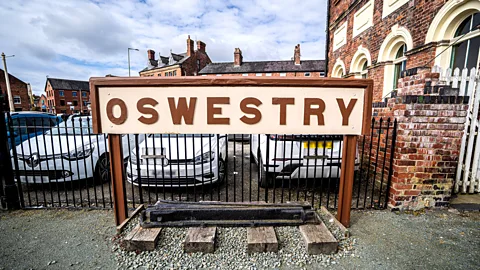 A large sign reading "Oswestry" outside the town's railway station with cars parked behind it (Credit: Richard Collett)