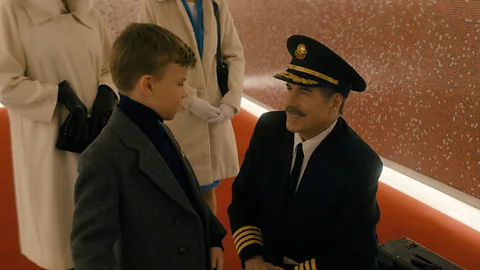 A still from Propeller One-Way Night Coach showing John Travolta as a pilot kneeling infront of a young boy (Credit: Apple TV)