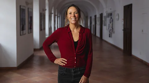 A portrait of neuroscientist Hanna Critchlow, standing in a corridor (Credit: Adam Mracek)