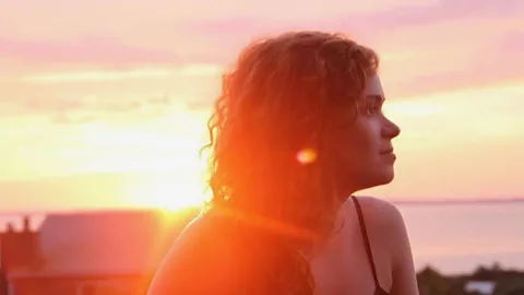 Ally Hirschlag pictured looking off camera with beams of sunlight from the sunset behind her in Cape Cod (Credit: Mark Stetson)